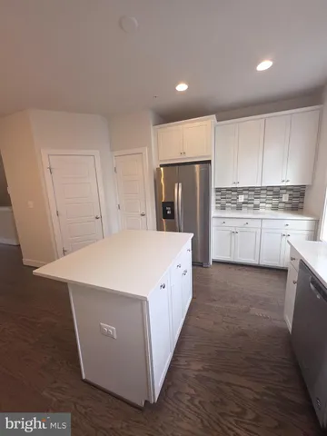 a large white kitchen with kitchen island a sink a refrigerator and a stove