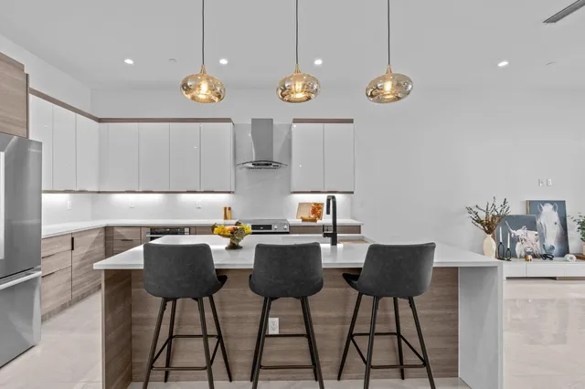 a kitchen with stainless steel appliances granite countertop a stove top oven a sink a dining table and chairs with wooden floor