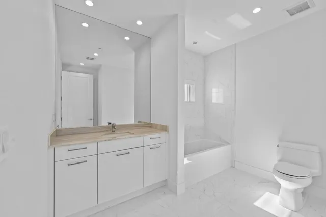 a bathroom with a granite countertop sink a toilet and bathtub