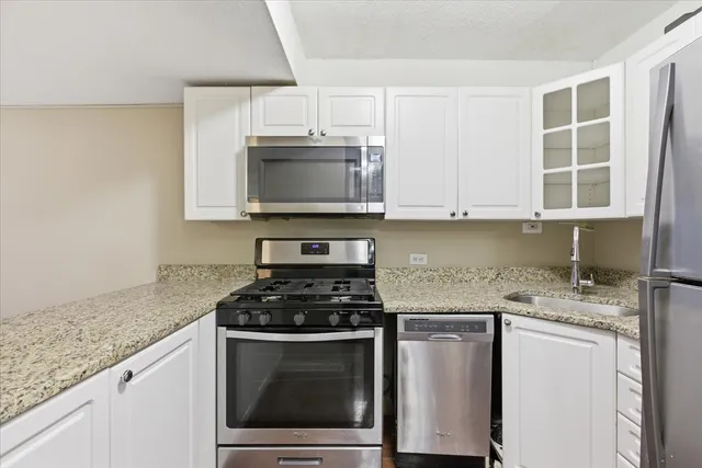 a kitchen with granite countertop a sink stove and microwave
