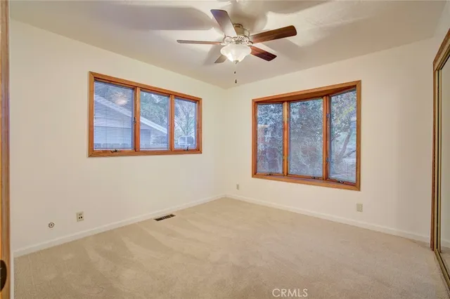 an empty room with windows and fan