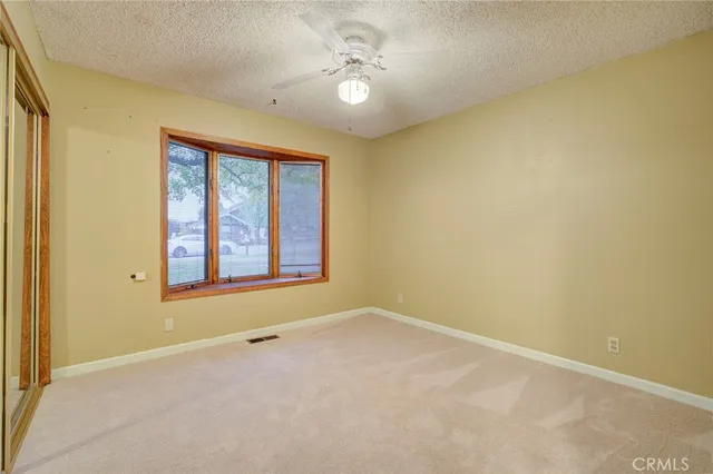 an empty room with a window and a ceiling fan