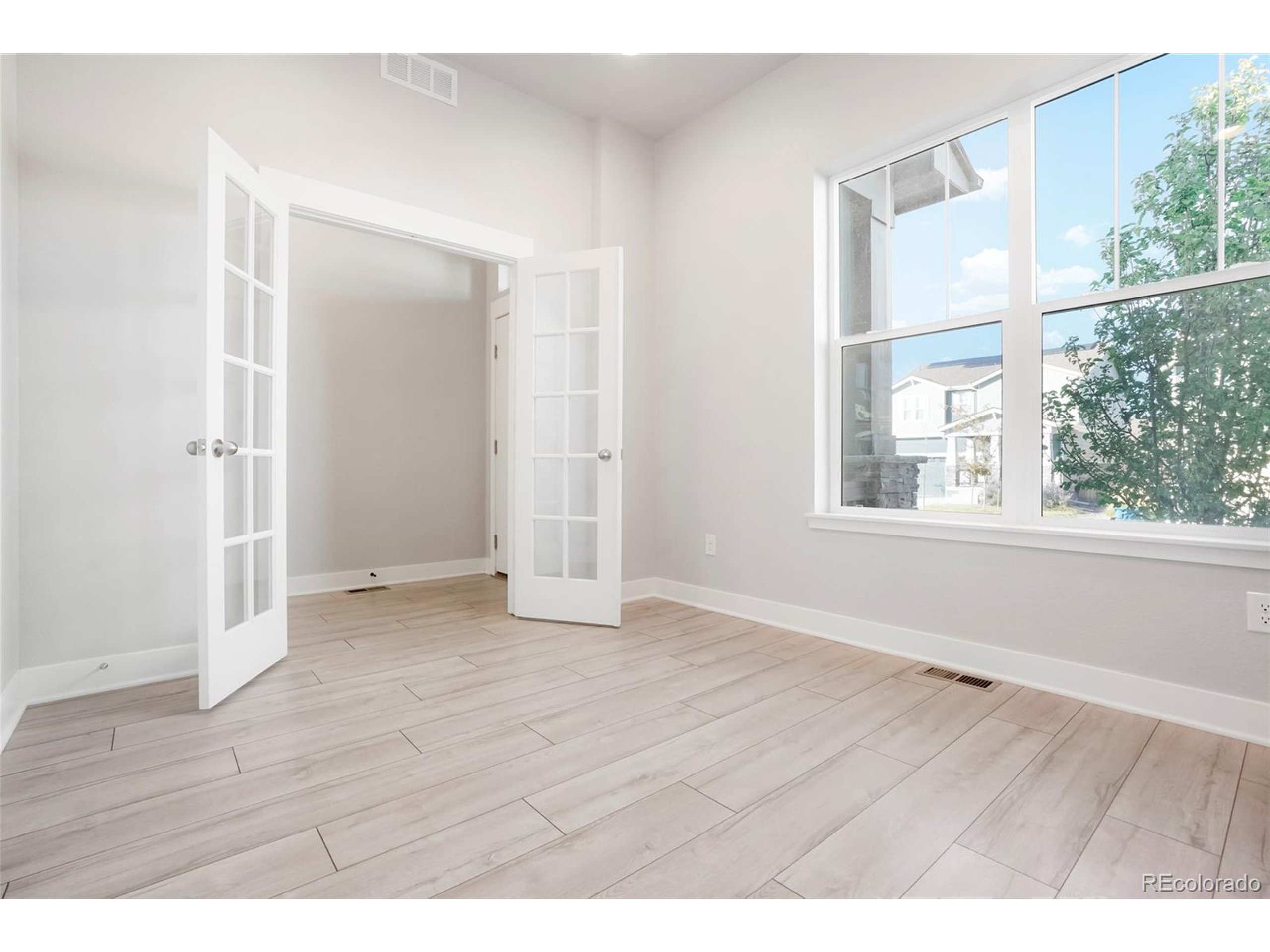 20968 East 60th Place Aurora, CO 80019 - Photo 18 of 50 a view of an empty room with wooden floor and windows