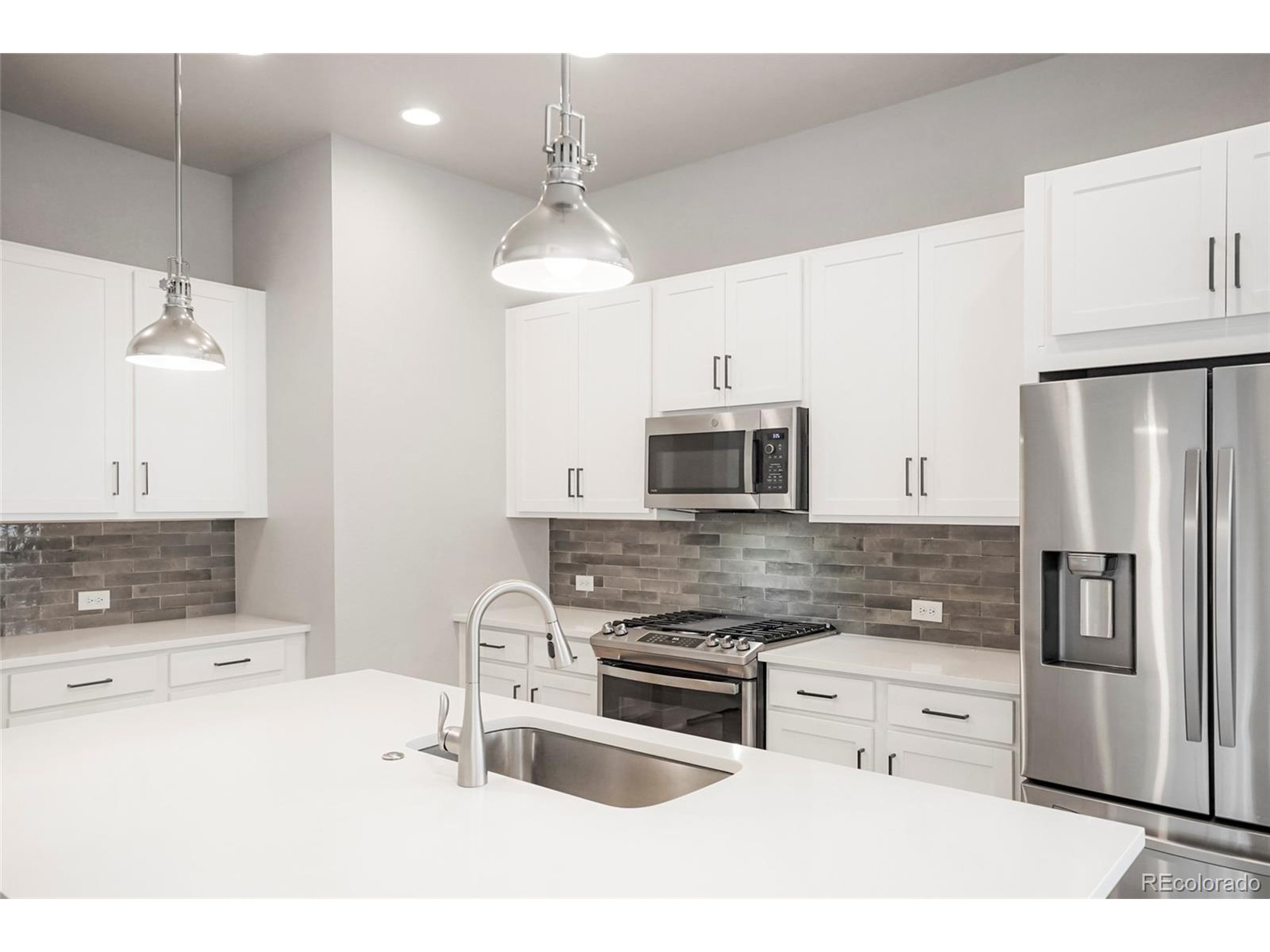 20968 East 60th Place Aurora, CO 80019 - Photo 4 of 50 a kitchen with stainless steel appliances a stove a sink and a refrigerator