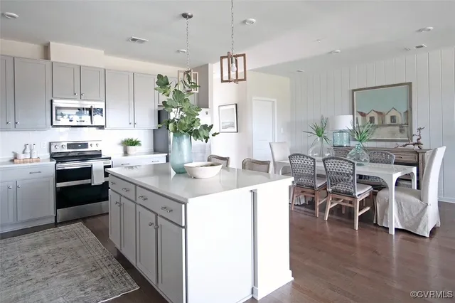 a kitchen with stainless steel appliances kitchen island granite countertop a table chairs and a refrigerator