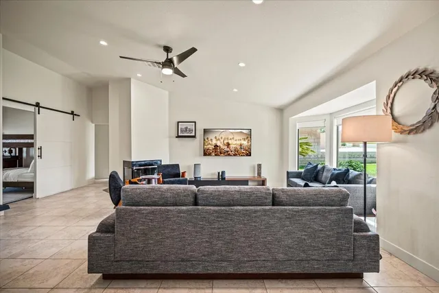 a living room with furniture a large window and wooden floor