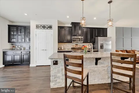 a kitchen with stainless steel appliances kitchen island granite countertop a stove a refrigerator a oven a kitchen island a stove and a refrigerator with wooden floor
