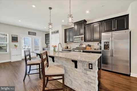 a kitchen with stainless steel appliances granite countertop a refrigerator a stove a sink dishwasher a dining table and chairs with wooden floor