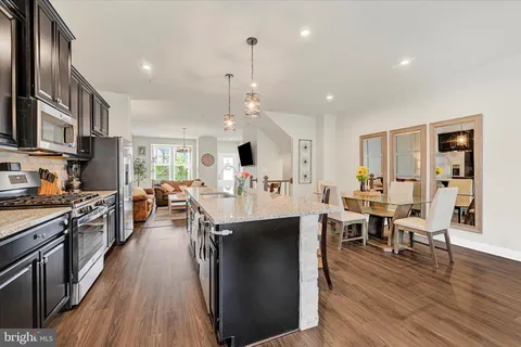 a view of a kitchen with kitchen island stainless steel appliances a dining table and chairs