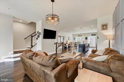 a living room with furniture kitchen view and a wooden floor
