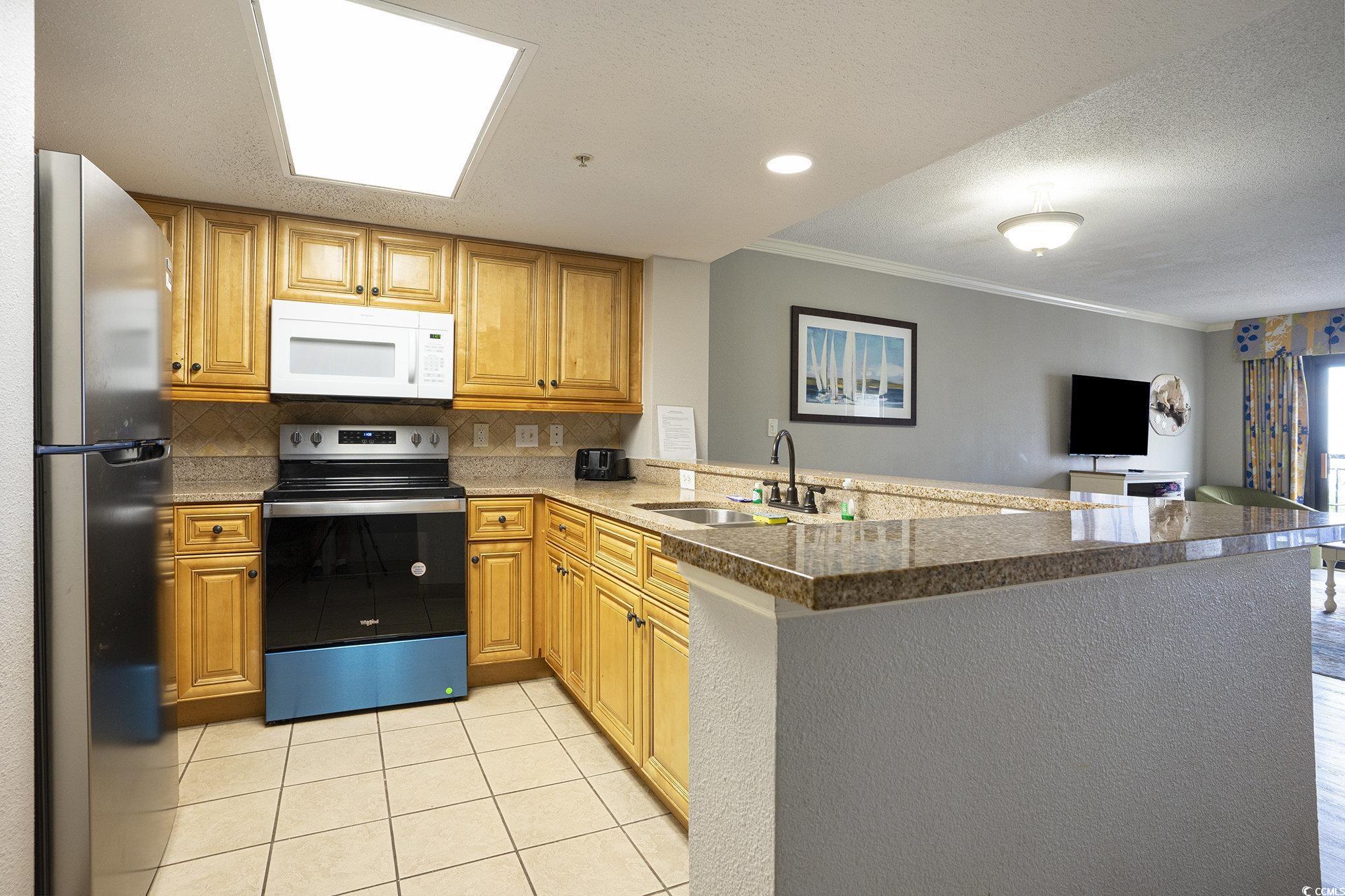 7100 North Ocean Boulevard, Unit 320 Myrtle Beach, SC 29572 - Photo 39 of 40 Kitchen featuring stainless steel appliances, a textured ceiling, open floor plan, a peninsula, and decorative backsplash