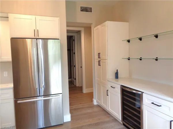 a kitchen with a refrigerator and white cabinets