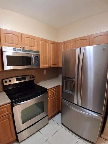 a kitchen with kitchen island granite countertop stainless steel appliances a refrigerator a stove top oven and sink