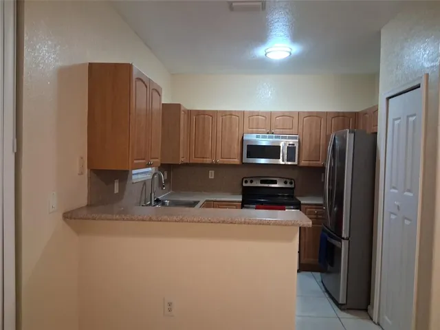 a kitchen with metallic refrigerator and white cabinets