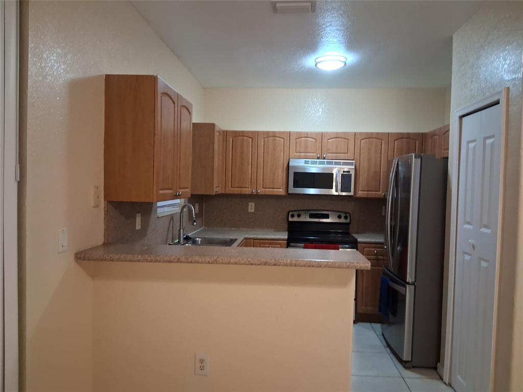 1425 Southeast 24th Court Homestead, FL 33035 - Photo 13 of 29 a kitchen with kitchen island granite countertop stainless steel appliances a refrigerator a stove top oven and sink