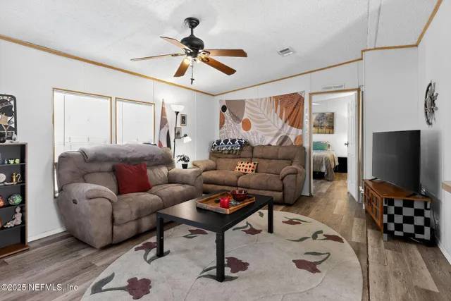 a living room with furniture a ceiling fan and a flat screen tv