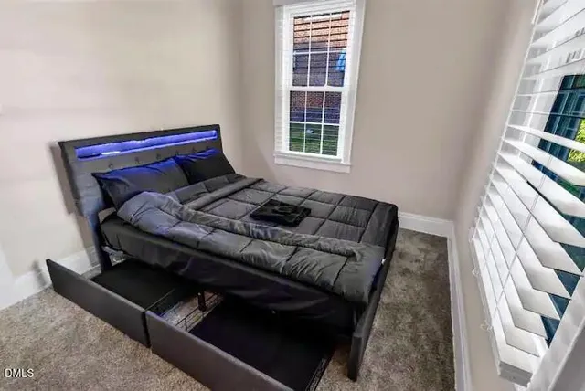 a bed sitting in a bedroom next to a window with a book shelf