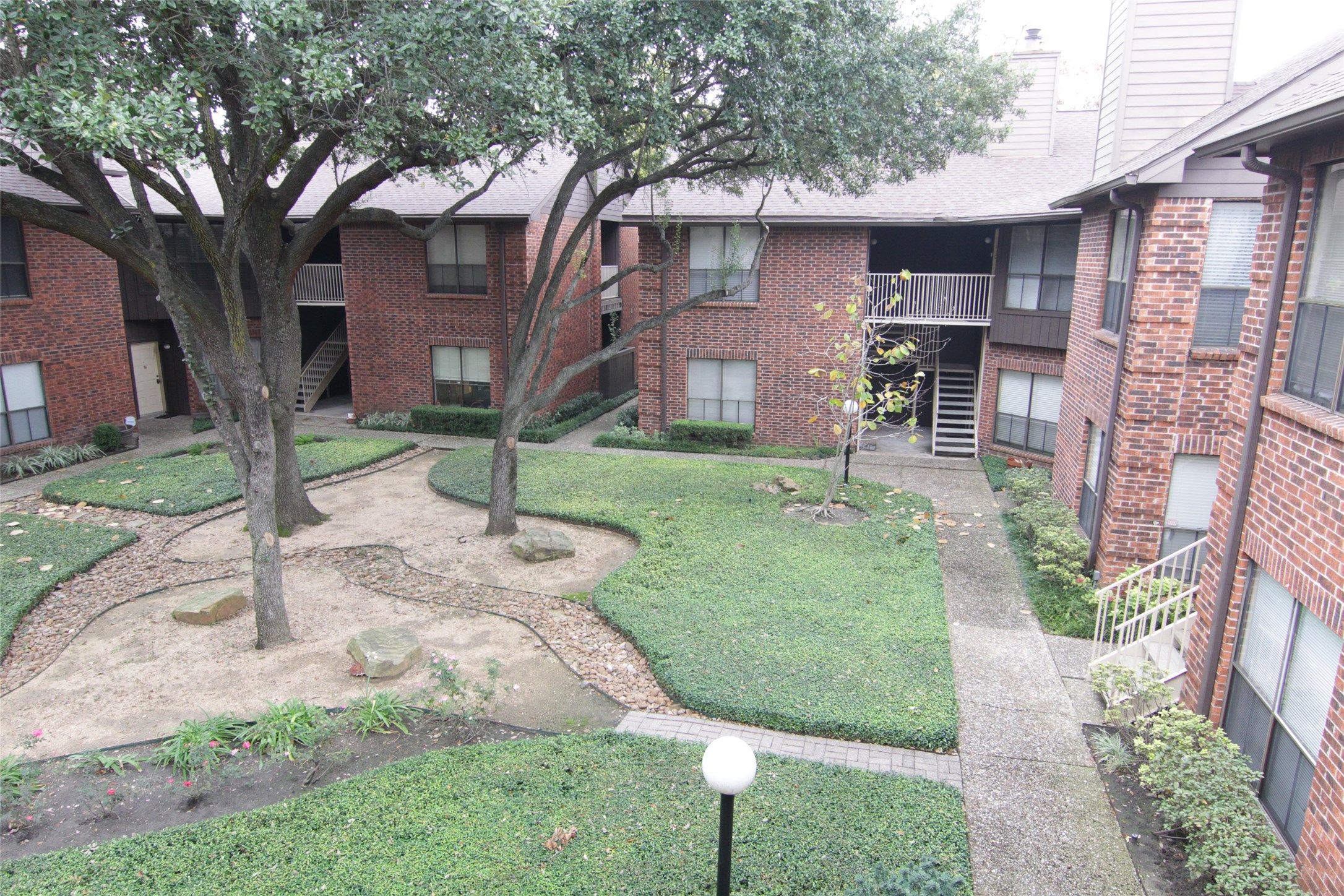 3100 Walnut Bend Lane, Unit 118 Houston, TX 77042 - Photo 18 of 20 a view of a yard in front of a brick house with a large tree