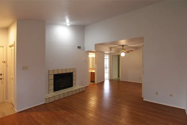 an empty room with wooden floor fireplace and windows