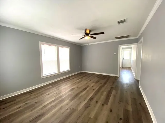 a view of empty room with wooden floor and fan