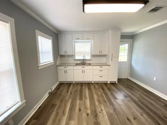 a view of a kitchen with wooden floor and electronic appliances