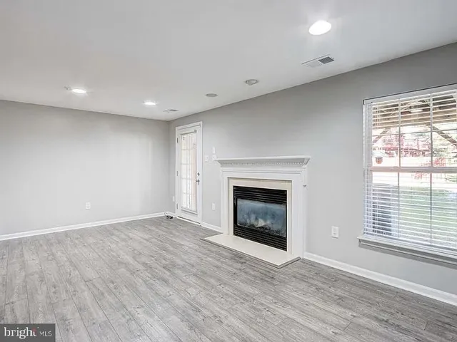 an empty room with wooden floor a fireplace and windows