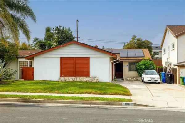 a front view of a house with a yard and potted plants