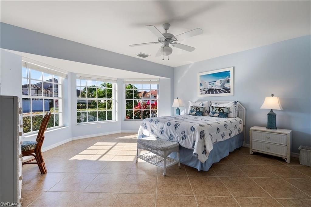 8432 Indian Wells Way Naples, FL 34113 - Photo 7 of 27 a spacious bedroom with a bed a chandelier and large window