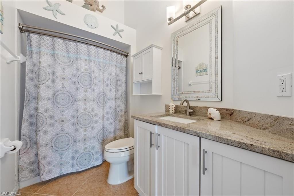 8432 Indian Wells Way Naples, FL 34113 - Photo 9 of 27 a bathroom with a granite countertop sink a toilet and a mirror
