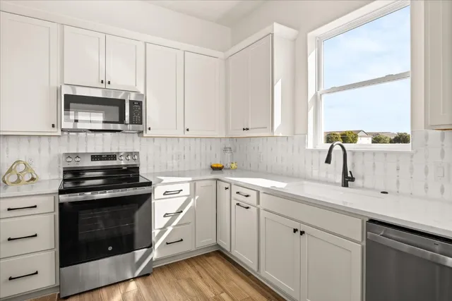 a kitchen with cabinets appliances a sink and a window