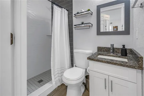 a bathroom with a granite countertop sink toilet and shower