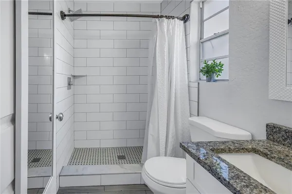 a bathroom with a granite countertop shower and a toilet