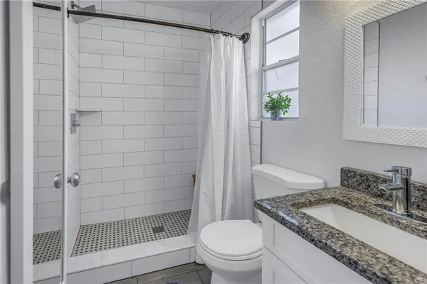 a bathroom with a granite countertop sink a toilet and shower