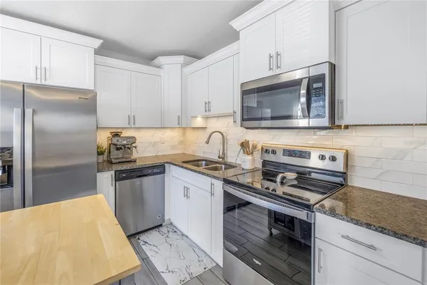 a kitchen with stainless steel appliances granite countertop a stove microwave refrigerator and sink