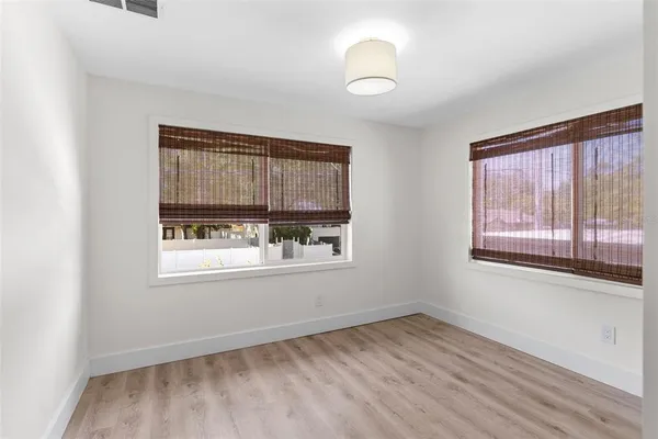 an empty room with wooden floor and windows