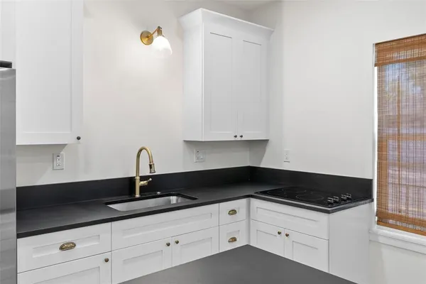 a kitchen with granite countertop white cabinets and black appliances