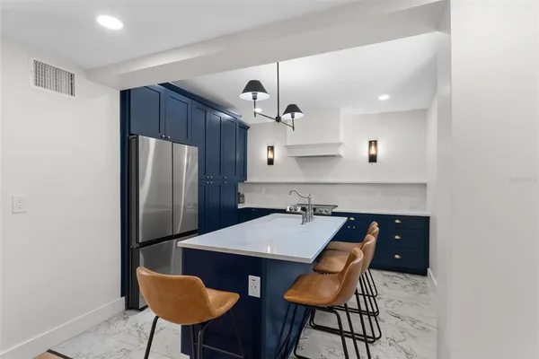 a kitchen with stainless steel appliances granite countertop a dining table chairs and a refrigerator