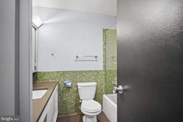 a bathroom with a granite countertop toilet a sink and mirror