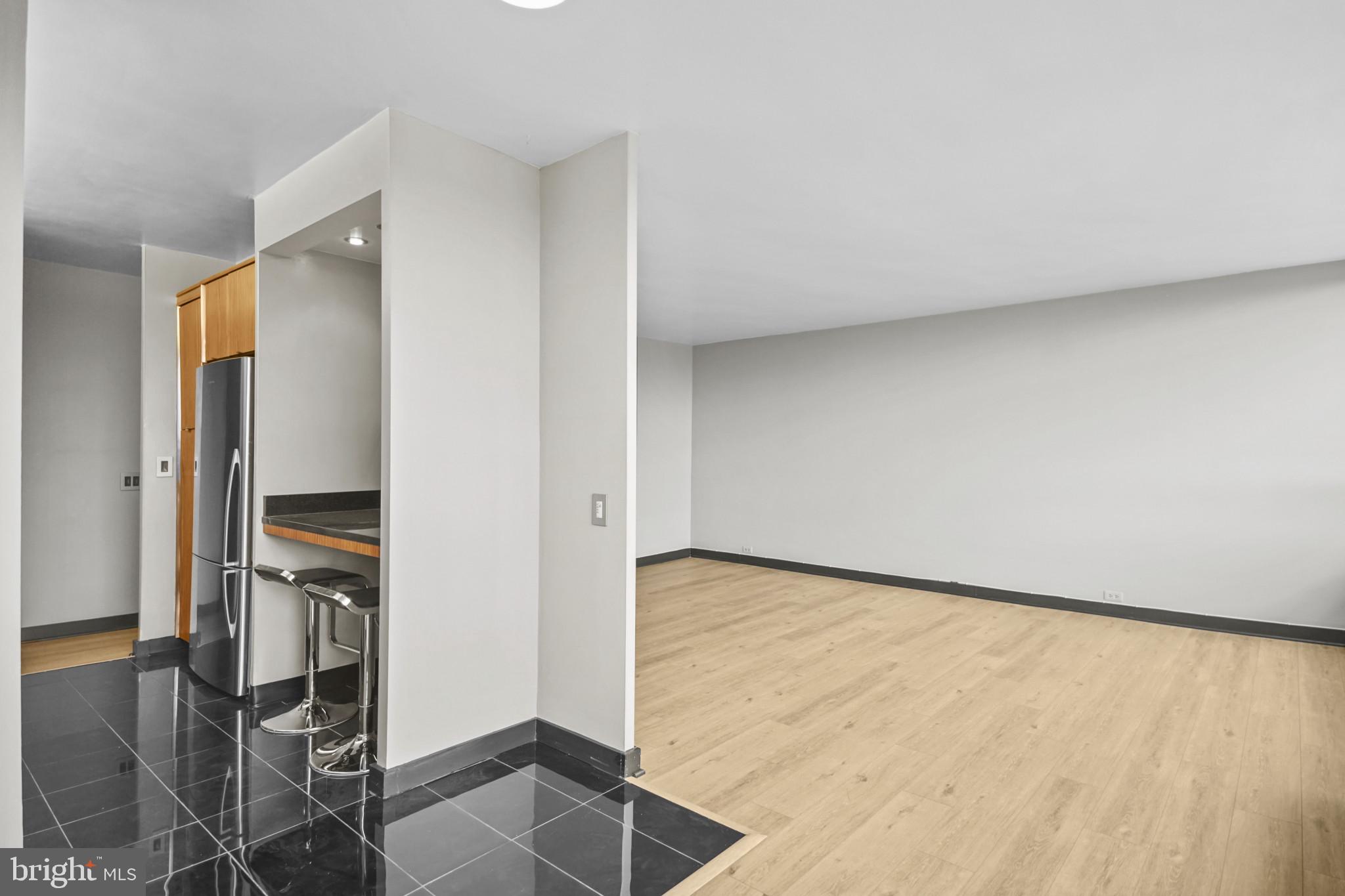 4000 North Charles Street, Unit 706 Baltimore, MD 21218 - Photo 5 of 23 an empty room with wooden floor and way to kitchen