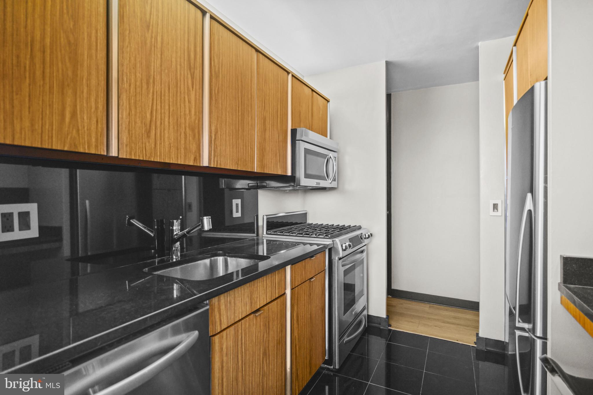 4000 North Charles Street, Unit 706 Baltimore, MD 21218 - Photo 10 of 23 a kitchen with stainless steel appliances granite countertop a sink a stove and a refrigerator