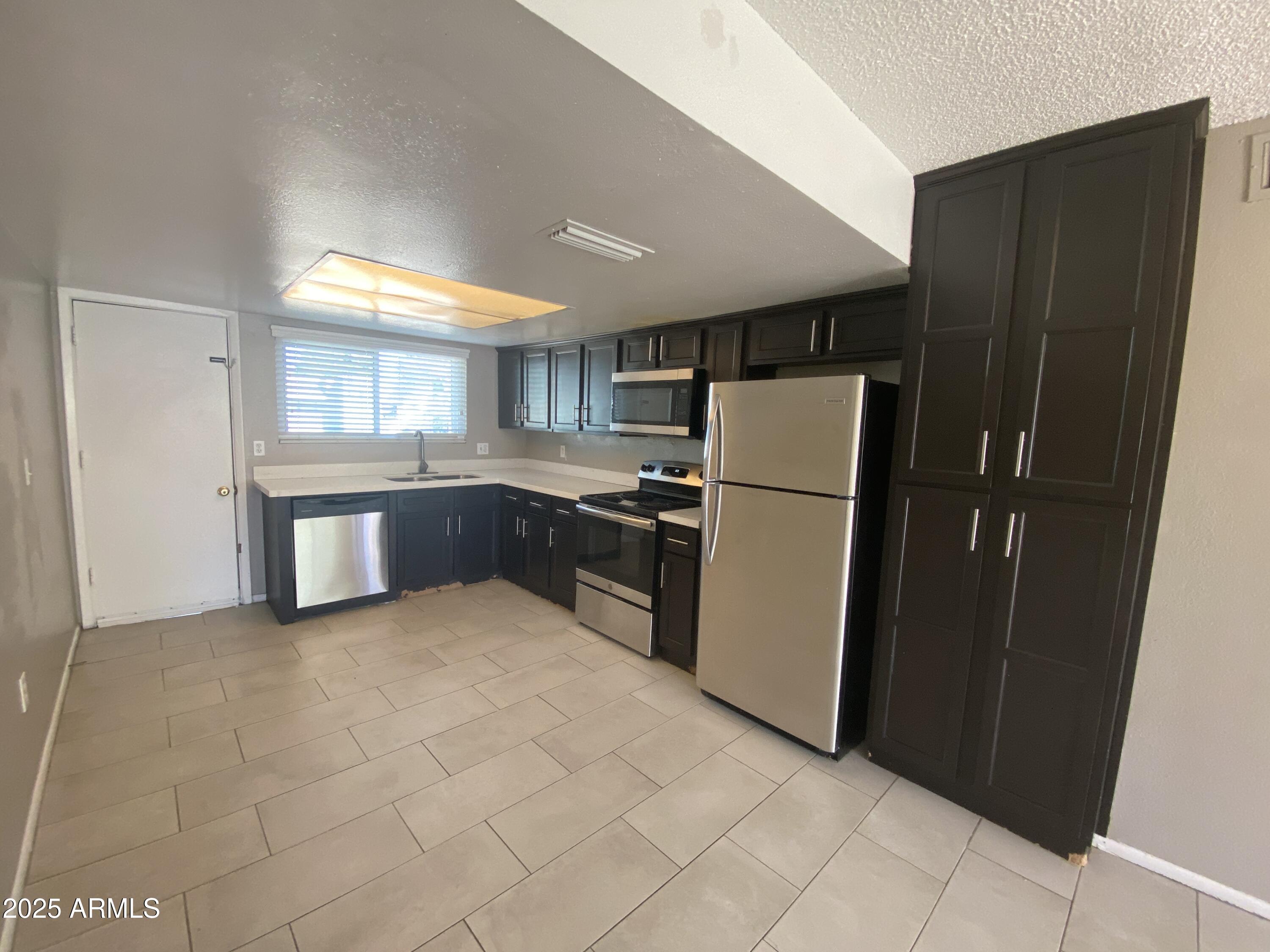 8122 North 33rd Avenue, Unit 3 Phoenix, AZ 85051 - Photo 2 of 11 a kitchen with granite countertop a refrigerator and a sink