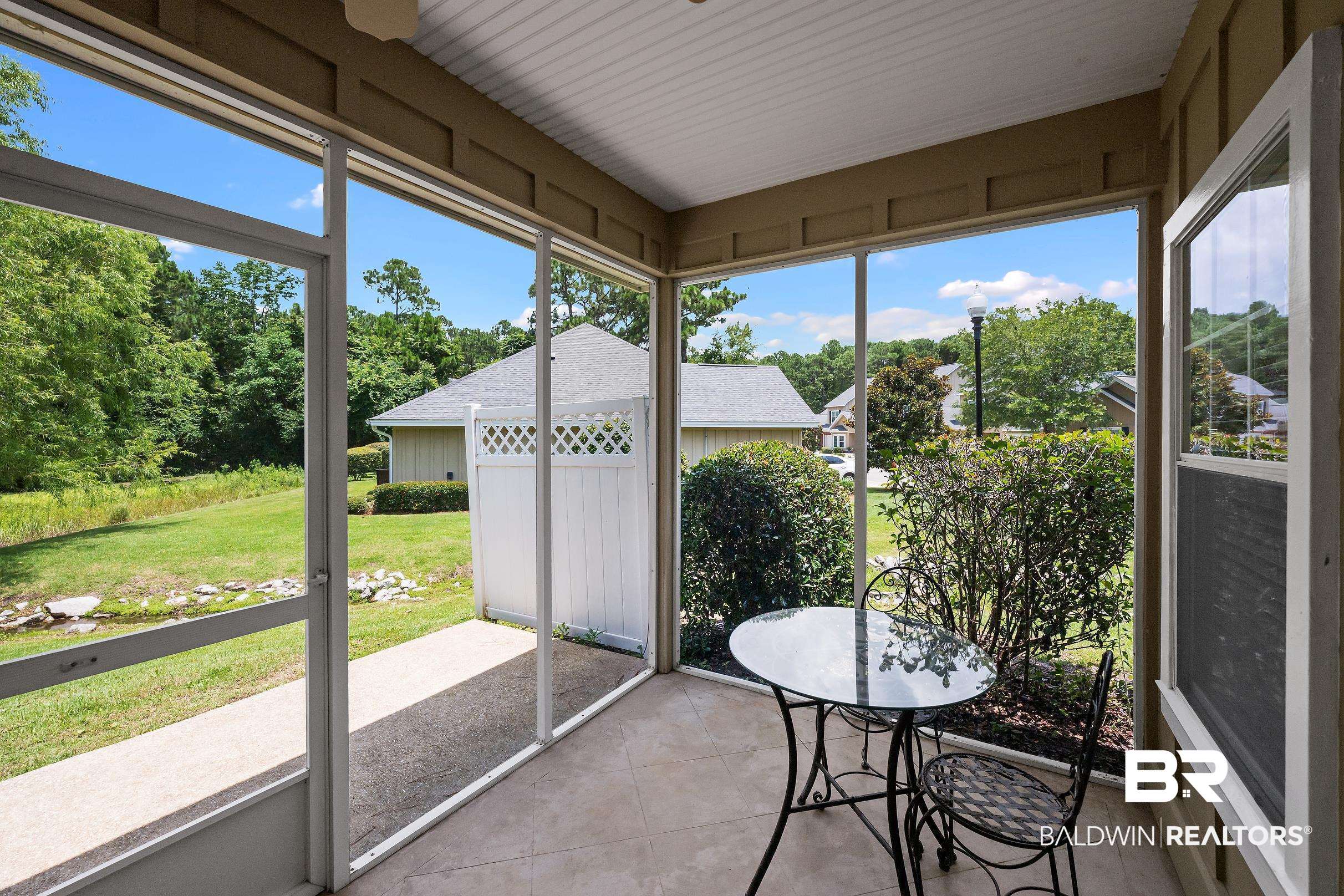 430 West Fort Morgan Road, Unit 704 Gulf Shores, AL 36542 - Photo 25 of 35 Screened-in porch featuring light-toned tile flooring, exposed beam ceiling details, and multiple window panels