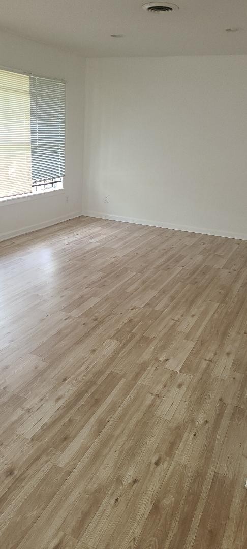 4423 Knotty Oaks Trail Houston, TX 77045 - Photo 2 of 12 an empty room with wooden floor and windows