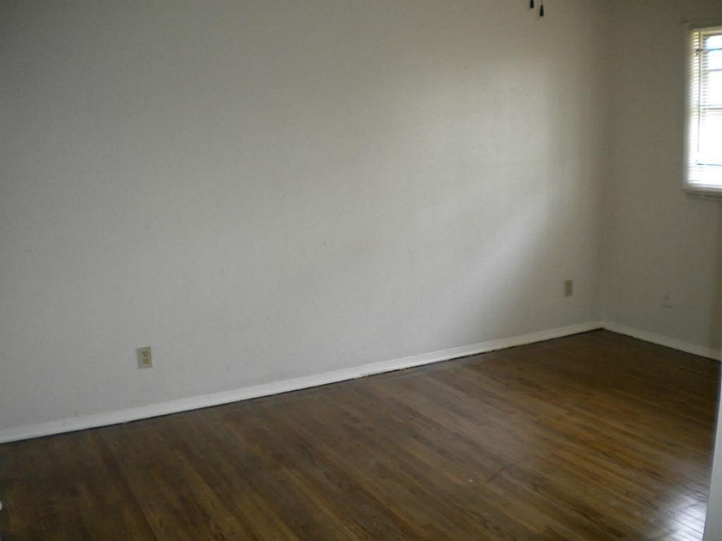 4423 Knotty Oaks Trail Houston, TX 77045 - Photo 9 of 12 an empty room with wooden floor and windows