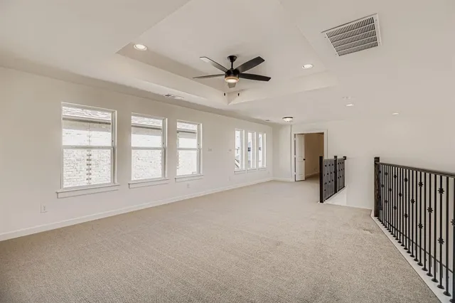 an empty room with windows and ceiling fan