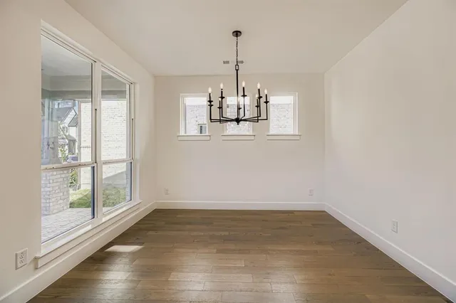 a view of a room with wooden floor chandelier and windows