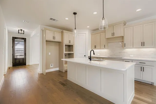 a kitchen with stainless steel appliances granite countertop a sink a stove a refrigerator and white cabinets