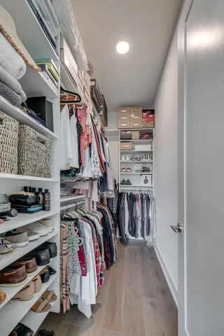 a view of walk in closet with clothes and shoes
