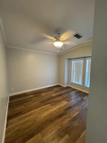 a view of an empty room with window and chandelier fan