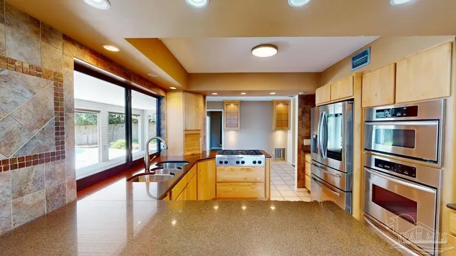 a large kitchen with stainless steel appliances a large window and a counter top space